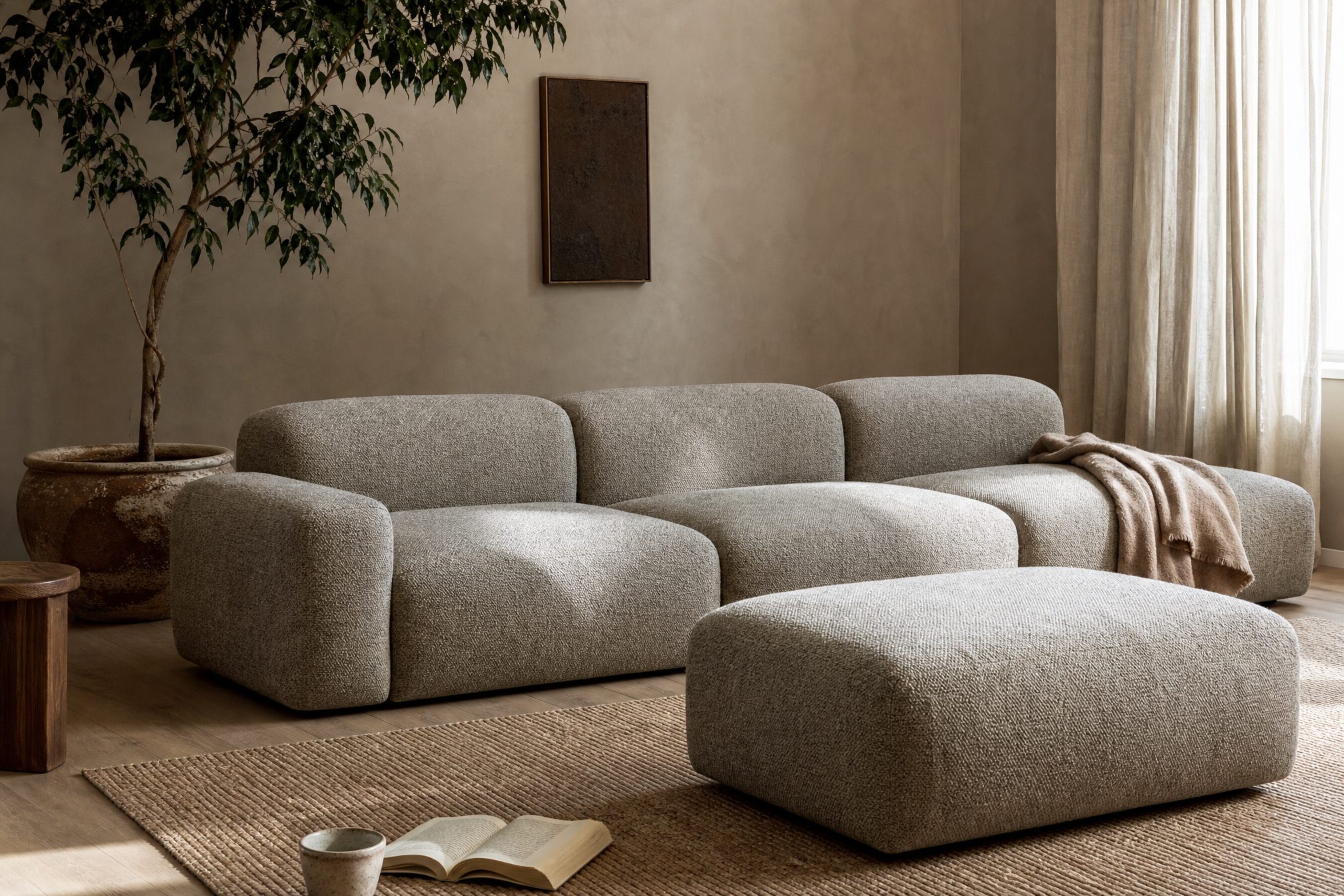 A pebble-grey modular sectional and ottoman in a calm living room