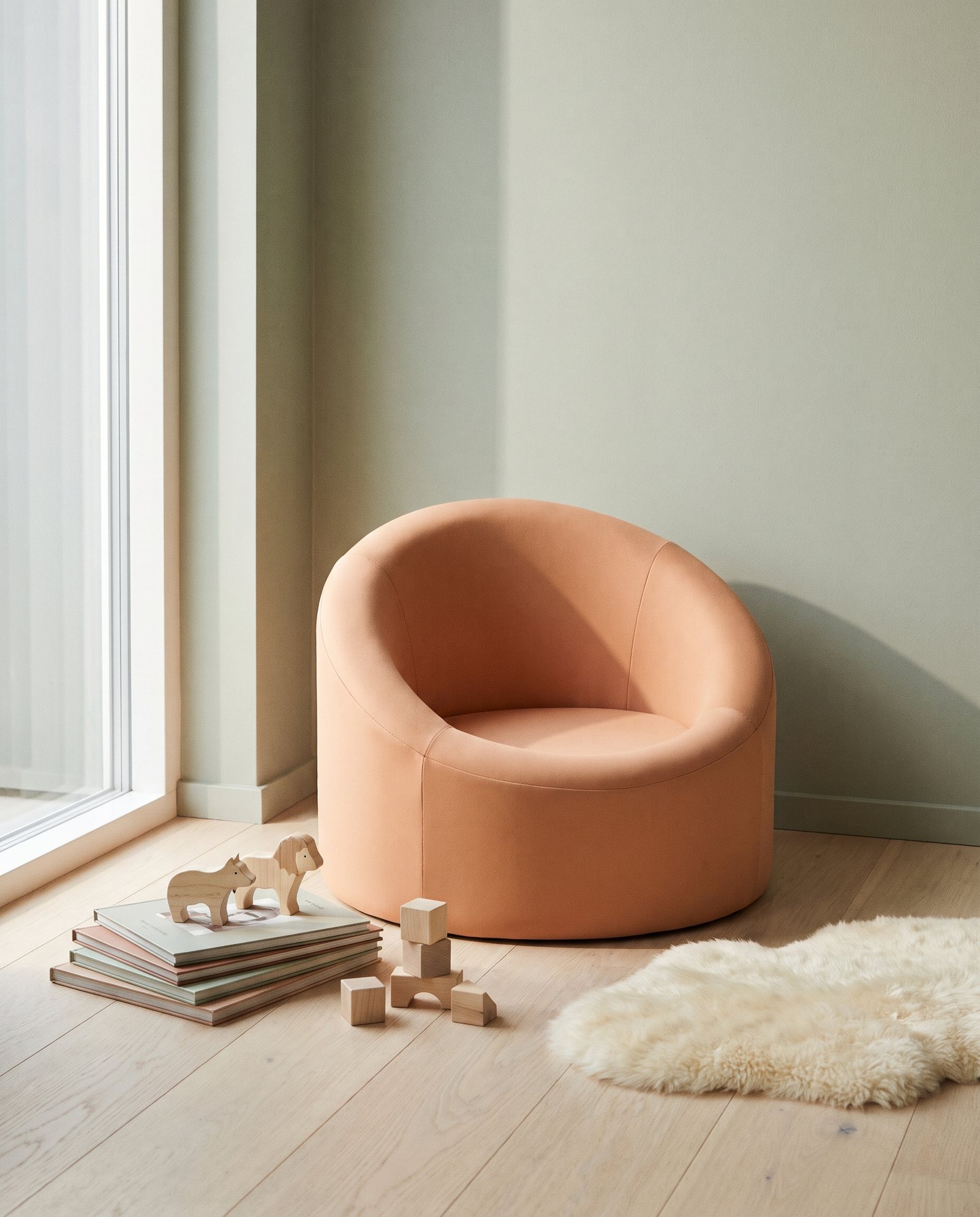 A small rounded floor chair in warm apricot beside picture books and wooden toys